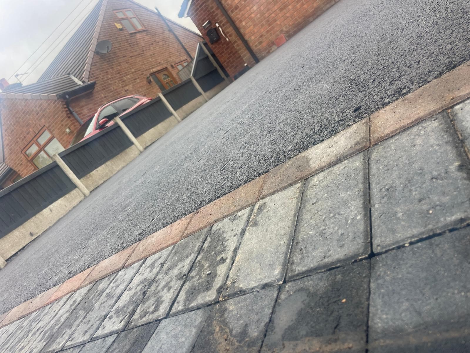 Freshly laid tarmac driveway with neat brick edging